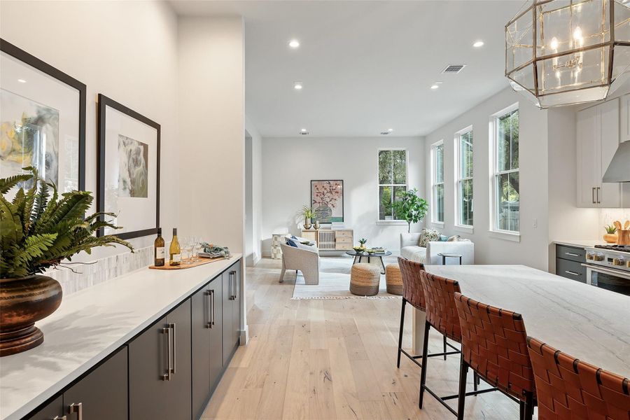 Kitchen with light stone countertops, decorative light fixtures, a kitchen breakfast bar, gray cabinets, and light wood-type flooring