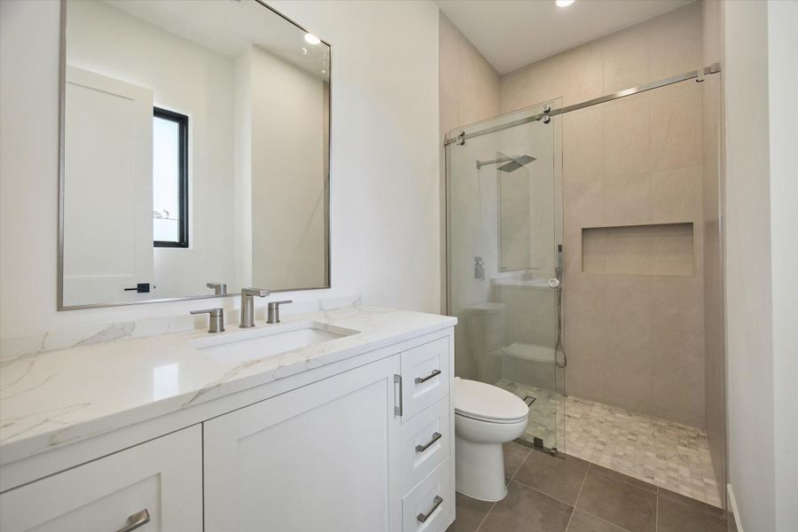 Guest bath with frameless glass shower and sleek designer fixtures. Guest bath with frameless glass shower and sleek designer fixtures.
