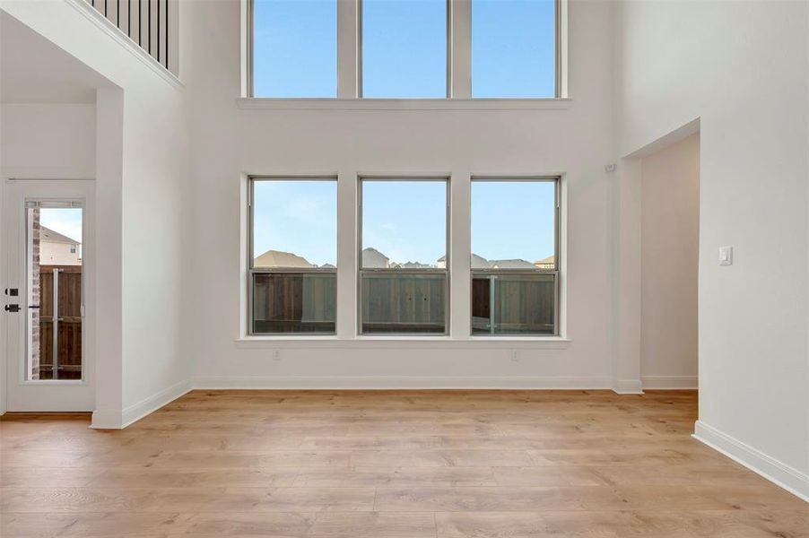 Unfurnished living room with a high ceiling, light wood finished floors, and plenty of natural light