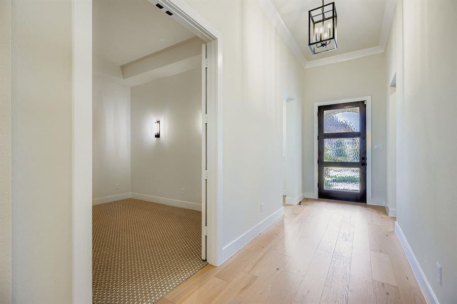 Entrance foyer with light wood-style flooring, crown molding, and a chandelier Entrance foyer with light wood-style flooring, crown molding, and a chandelier