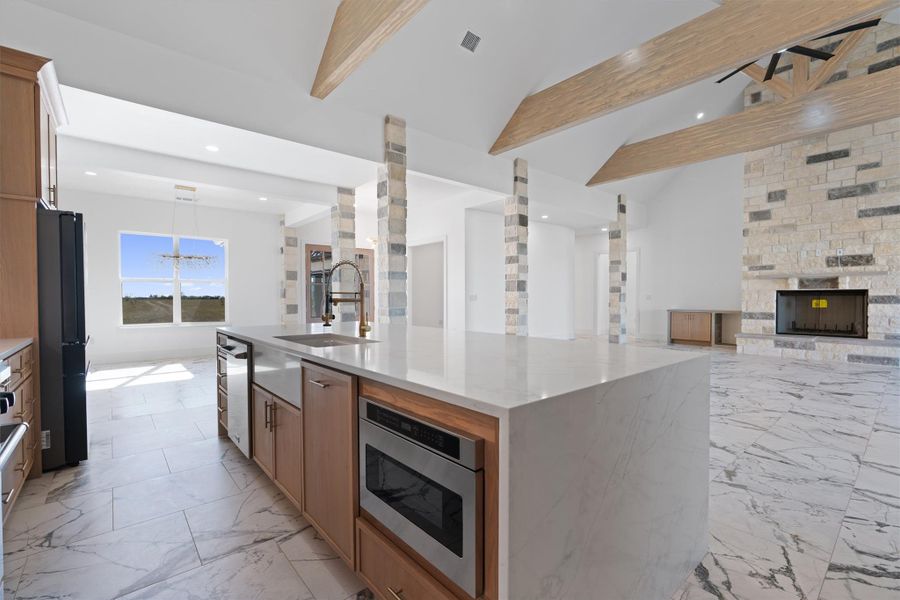 An open concept design seamlessly connects the kitchen and living area, highlighted by a majestic stone fireplace. An open concept design seamlessly connects the kitchen and living area, highlighted by a majestic stone fireplace.