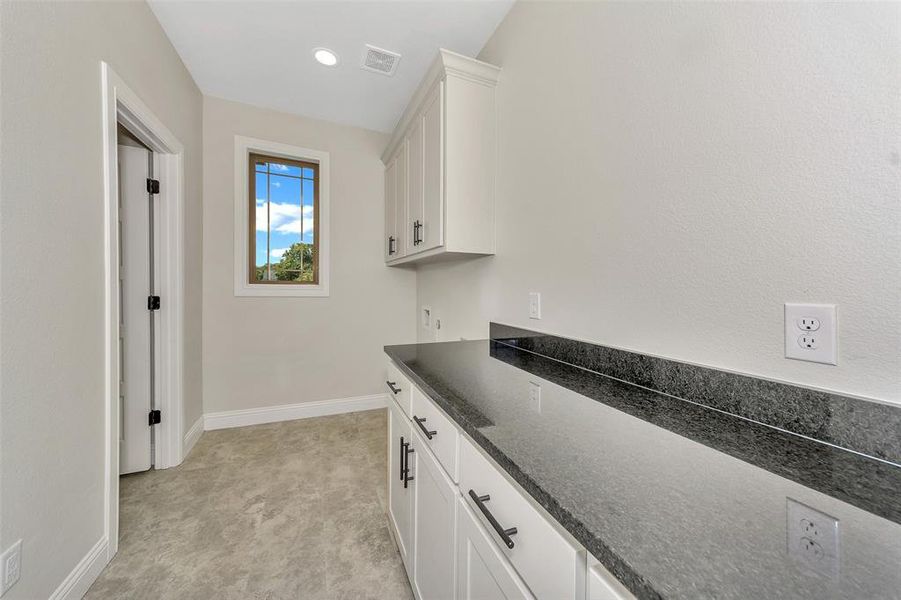 Kitchen featuring dark stone counters and white cabinets