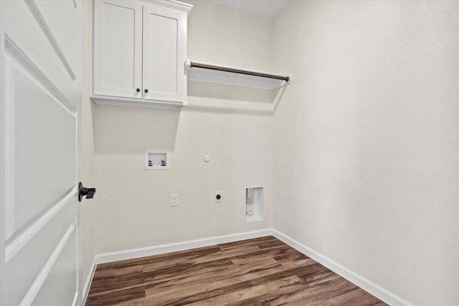 Washroom featuring dark wood finished floors, hookup for a gas dryer, hookup for a washing machine, electric dryer hookup, and cabinet space Washroom featuring dark wood finished floors, hookup for a gas dryer, hookup for a washing machine, electric dryer hookup, and cabinet space