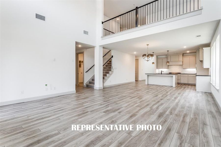 The family room is open to the game room upstairs creating multiple levels of open concept space for entertaining!  REPRESENTATIVE PHOTO.