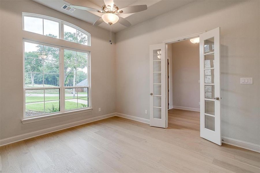 Unfurnished room featuring plenty of natural light, french doors, ceiling fan, and light hardwood / wood-style floors