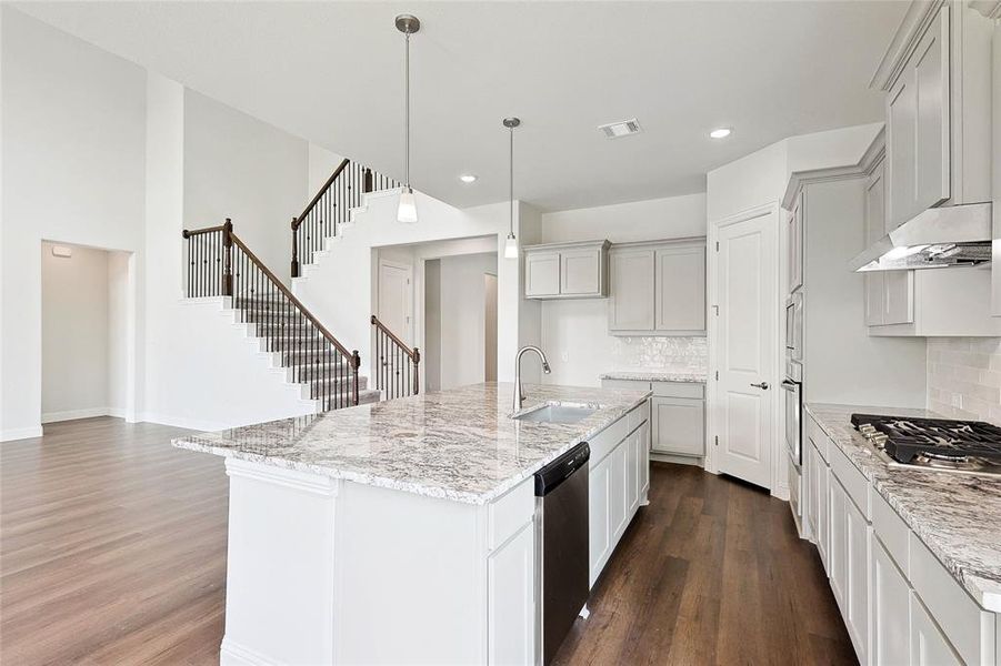 Kitchen with appliances with stainless steel finishes, dark hardwood / wood-style floors, backsplash, and an island with sink