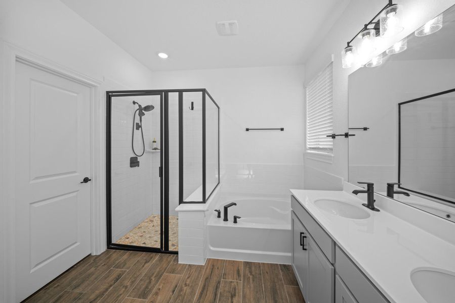 Full bathroom featuring double vanity, wood finish floors, a bath, and a shower stall Full bathroom featuring double vanity, wood finish floors, a bath, and a shower stall