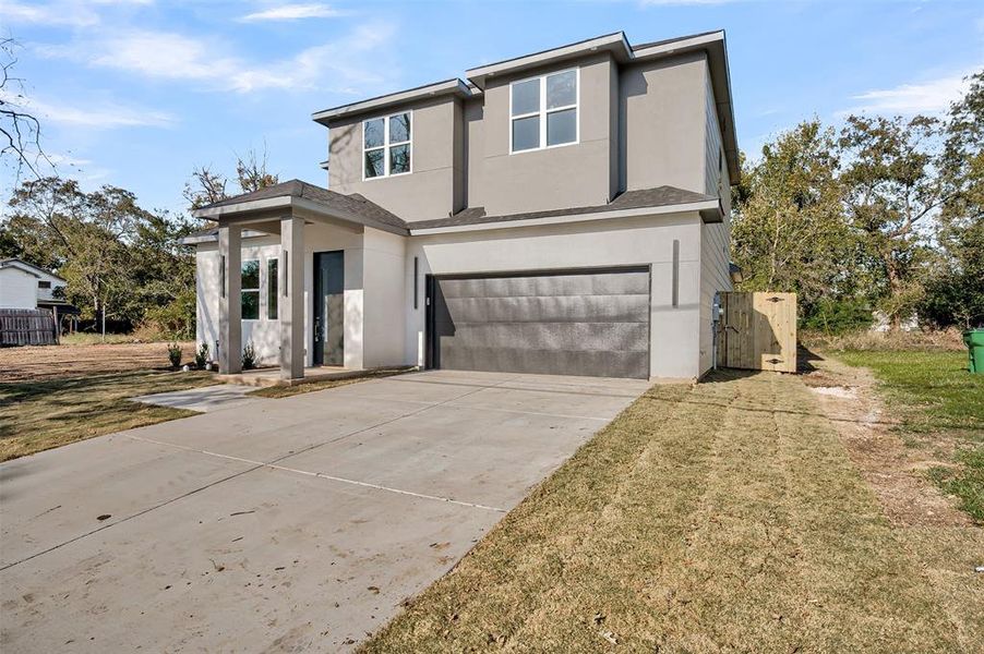 Modern home featuring stucco siding, a garage, concrete driveway, and a gate