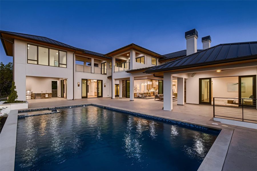 The property features a large outdoor patio with a swimming pool, an outdoor kitchen, and multiple balconies