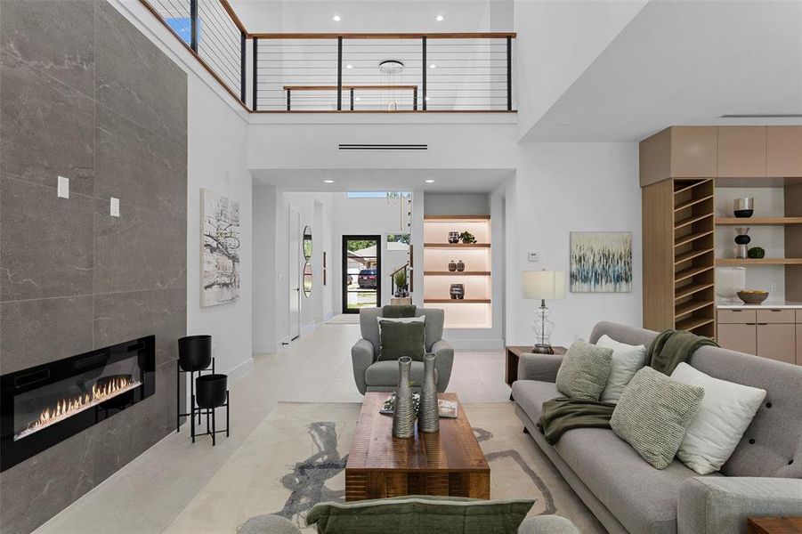 Living room featuring a high ceiling, a tiled fireplace, and light tile patterned flooring