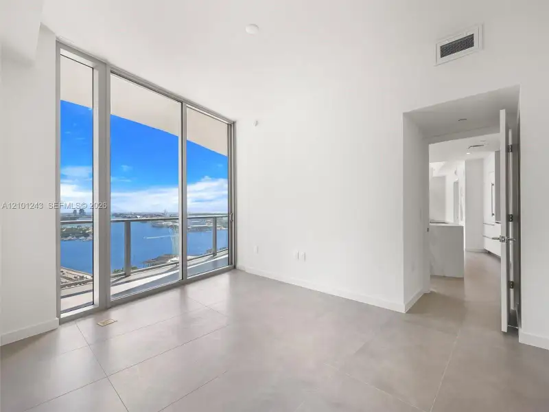 Floor-to-ceiling glass windows, private balcony, neutral tile flooring, and metal-framed sliding glass doors Floor-to-ceiling glass windows, private balcony, neutral tile flooring, and metal-framed sliding glass doors