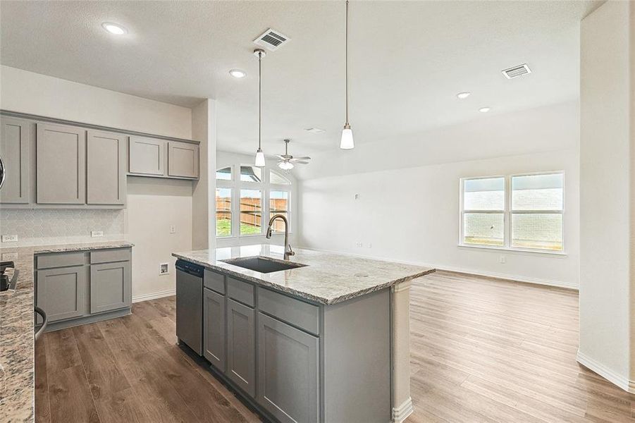 Kitchen featuring light stone counters, stainless steel dishwasher, sink, and plenty of natural light