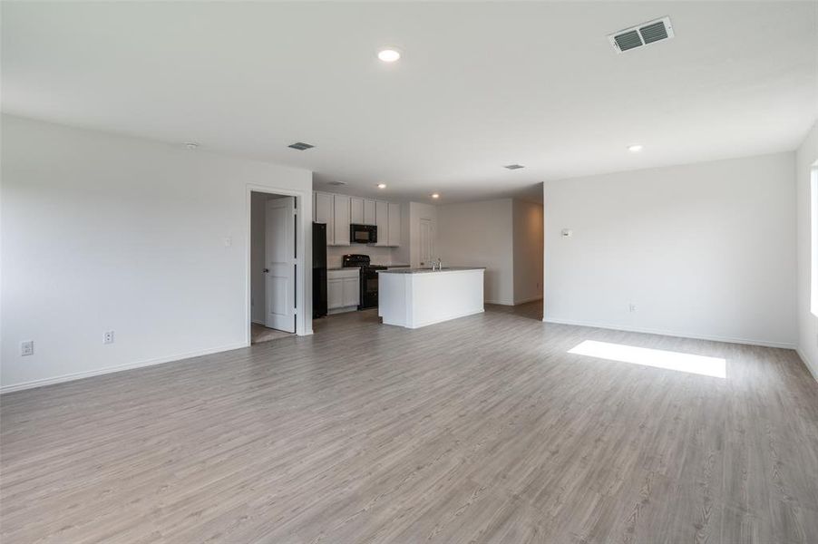 Unfurnished living room with sink and light hardwood / wood-style floors