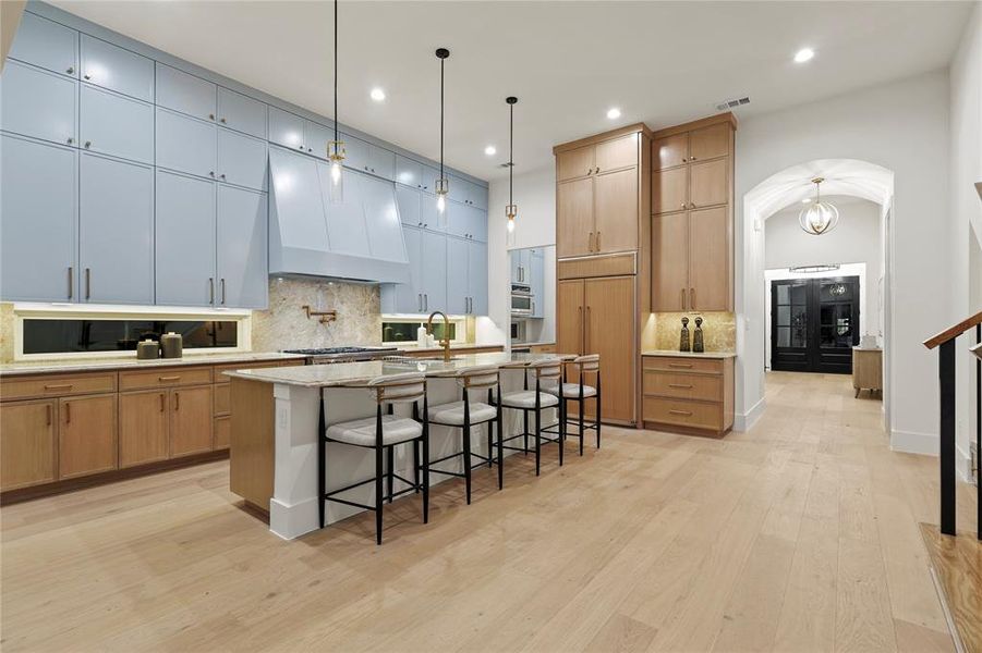 Kitchen with backsplash, arched walkways, a breakfast bar, pendant lighting, and recessed lighting