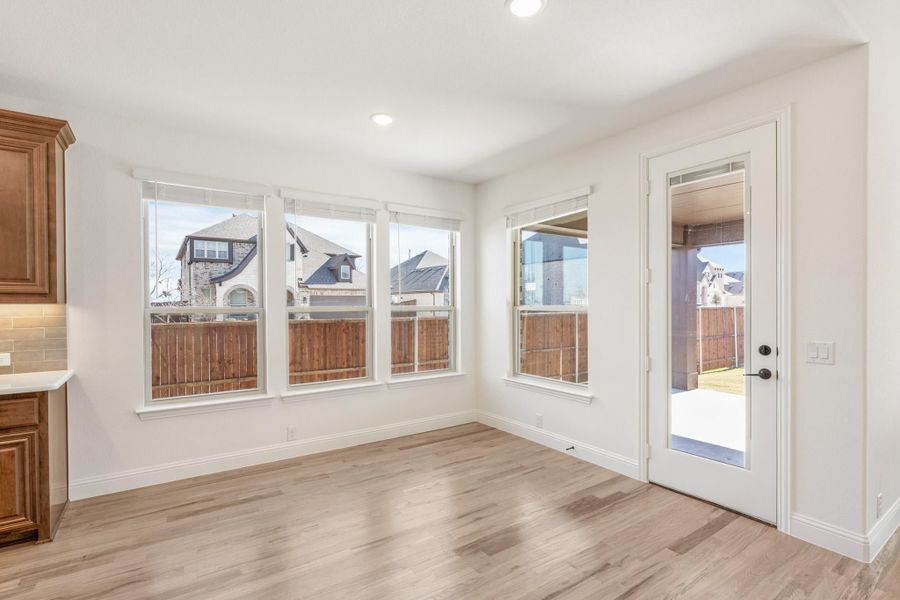 Bright breakfast nook with hardwood floors, large windows, and glass back door leading to patio