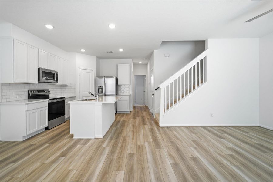 Kitchen with stainless steel appliances, white cabinetry, tasteful backsplash, open floor plan, and recessed lighting Kitchen with stainless steel appliances, white cabinetry, tasteful backsplash, open floor plan, and recessed lighting