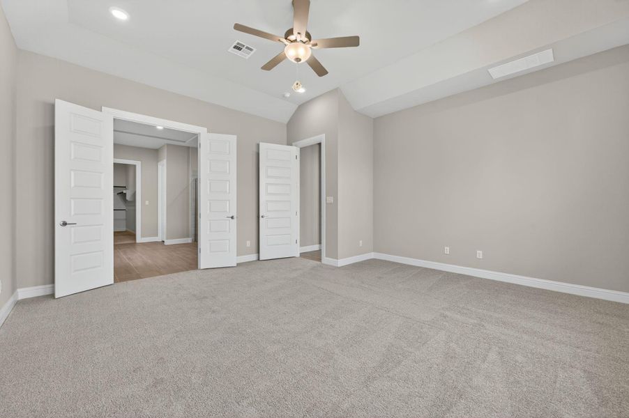 Unfurnished bedroom featuring light colored carpet, a ceiling fan, lofted ceiling, and recessed lighting