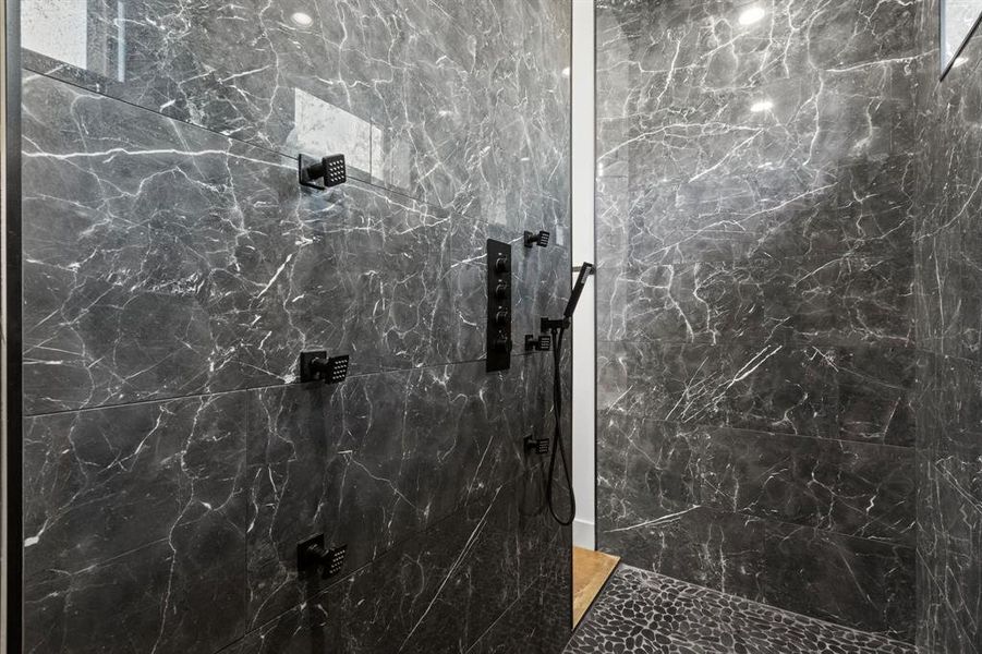 The Drive-thru shower welcomes beautiful lighting and natural light. This custom shower designed with eight zones, including a large overhead rainfall shower fixture.