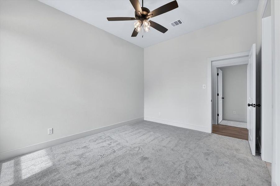 Empty room with light colored carpet and ceiling fan
