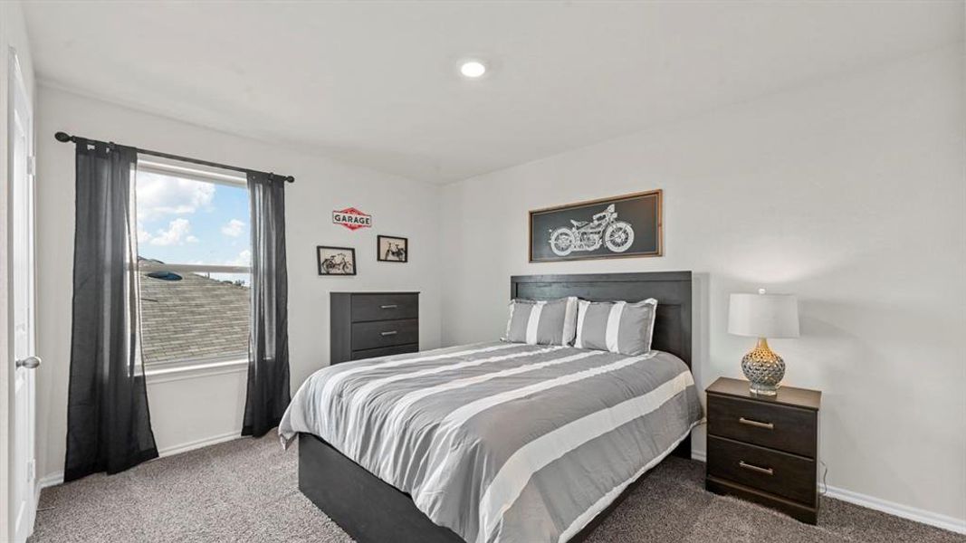 This bedroom features a window with views of the sky and a roofline, carpeted flooring, and a ceiling light fixture This bedroom features a window with views of the sky and a roofline, carpeted flooring, and a ceiling light fixture
