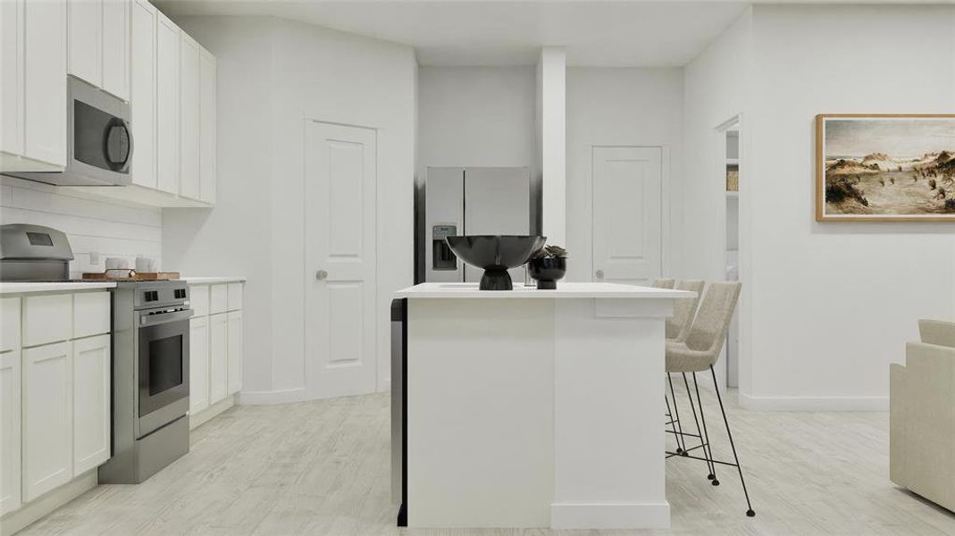 Kitchen with appliances with stainless steel finishes, a kitchen island, light countertops, white cabinetry, and a breakfast bar