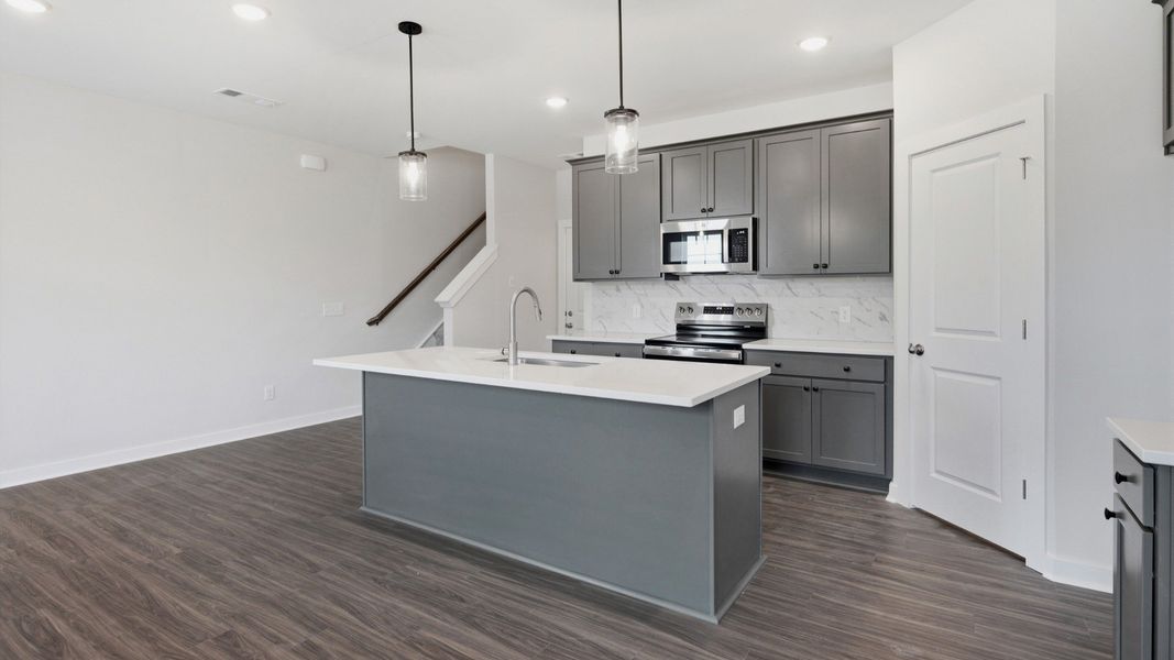 Grey cabinets in kitchen with white quartz backsplash