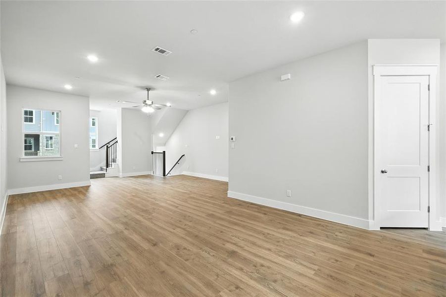 Unfurnished living room with recessed lighting, light wood-style flooring, a ceiling fan, and stairway