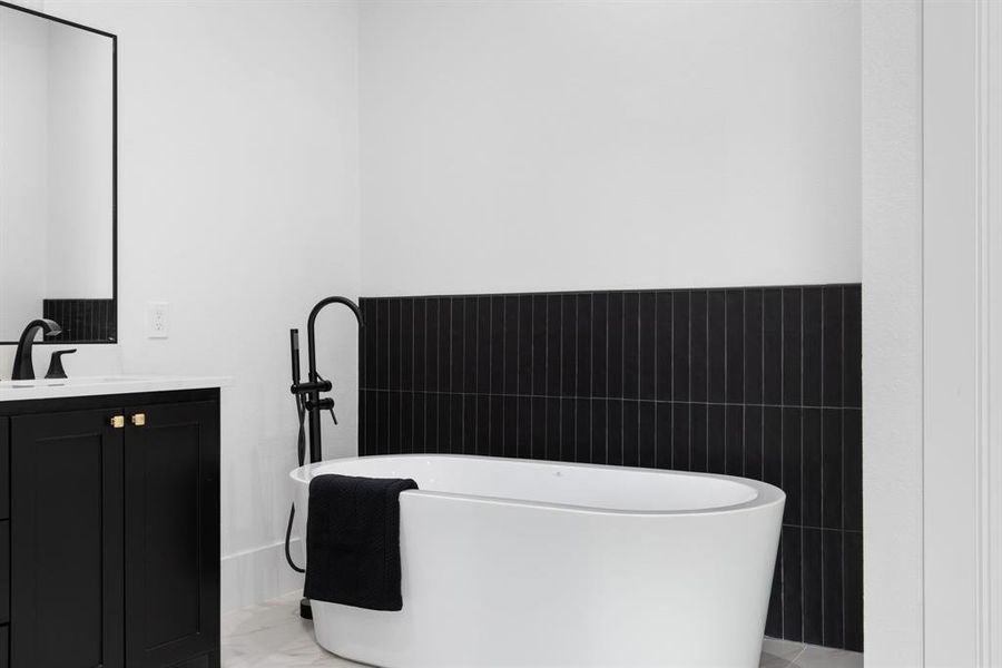 Bathroom with vanity, a bath, and tile walls