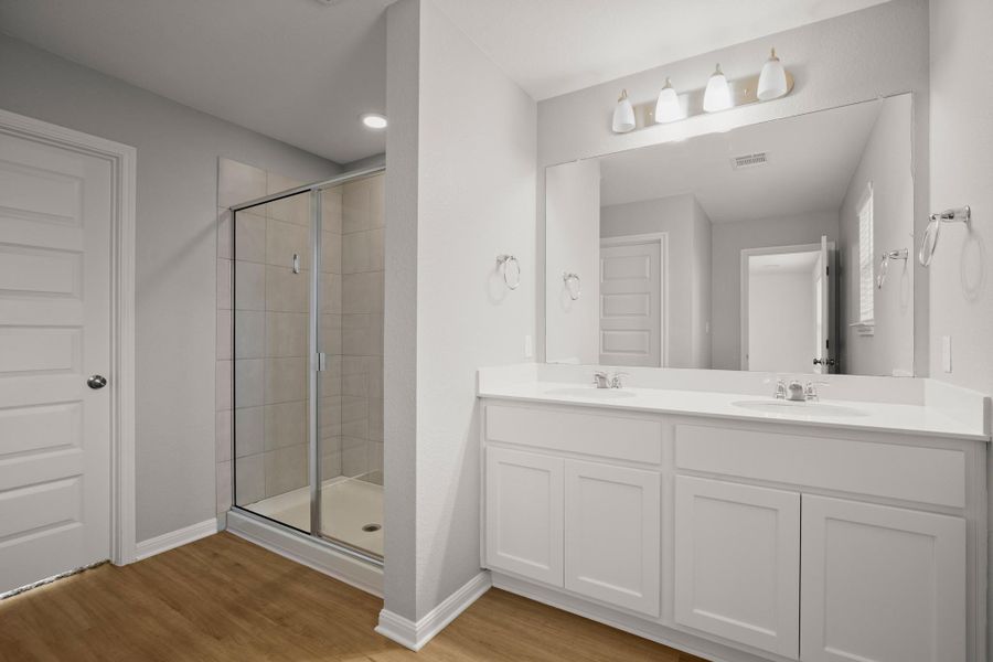 Bathroom featuring a stall shower, wood finished floors, and double vanity