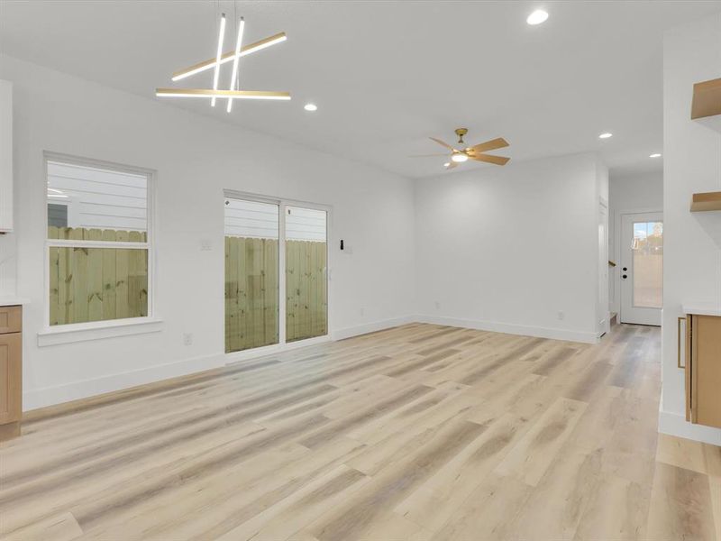 Unfurnished living room featuring light hardwood / wood-style flooring and ceiling fan with notable chandelier