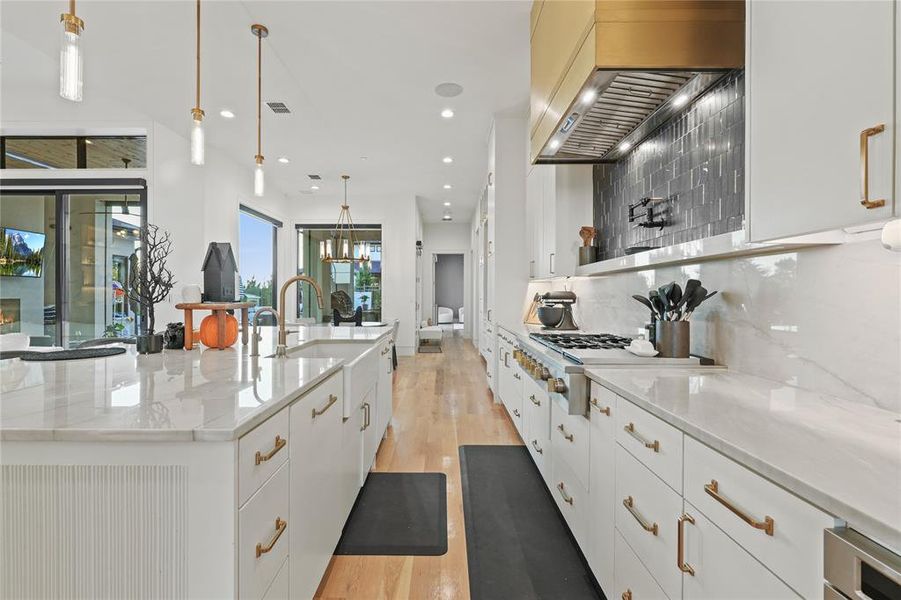 Kitchen with light stone countertops, backsplash, white cabinets, light wood-style flooring, and recessed lighting Kitchen with light stone countertops, backsplash, white cabinets, light wood-style flooring, and recessed lighting