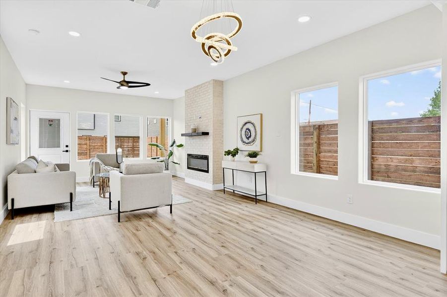 Open-concept living area featuring light wood-finish flooring, recessed lighting, and a modern chandelier