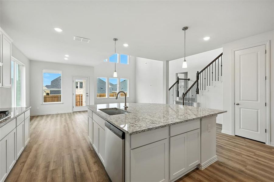 Kitchen featuring hanging light fixtures, light stone countertops, and dishwasher