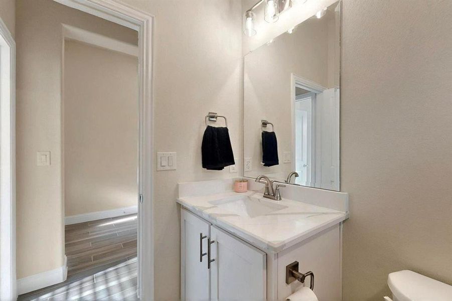 Full bath featuring vanity, toilet, bath shower combo baseboards, and wood finished floors