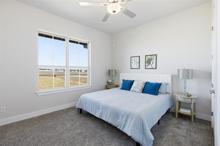 Carpeted bedroom with ceiling fan and baseboards