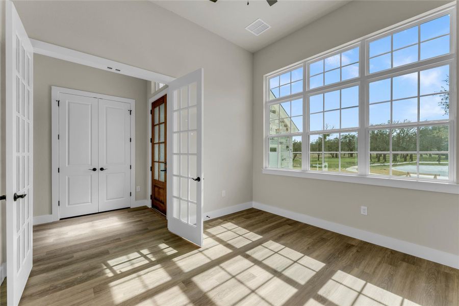 Unfurnished bedroom featuring french doors, light wood-style flooring, a ceiling fan, and a closet