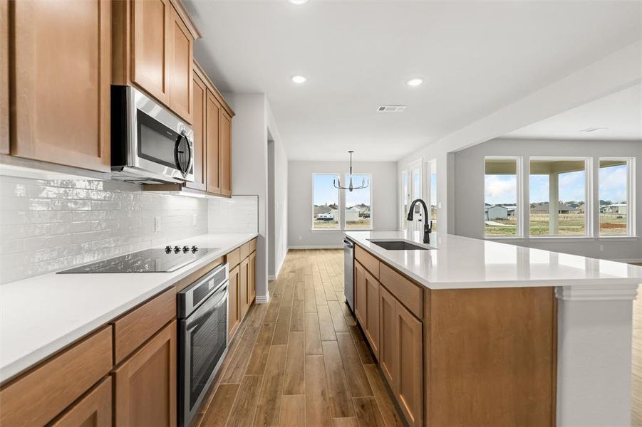 Kitchen with brown cabinetry, appliances with stainless steel finishes, wood finish floors, tasteful backsplash, and recessed lighting Kitchen with brown cabinetry, appliances with stainless steel finishes, wood finish floors, tasteful backsplash, and recessed lighting