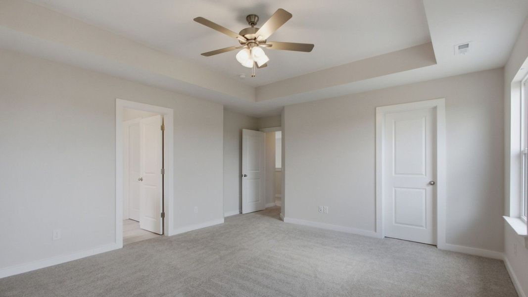 Large primary bedroom with doors to en-suite bathroom and large walk-in closet