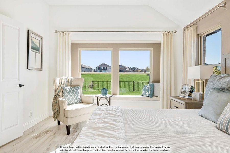 Bright bedroom with vaulted ceiling, window seat, accent chair, and large windows overlooking a green yard Bright bedroom with vaulted ceiling, window seat, accent chair, and large windows overlooking a green yard