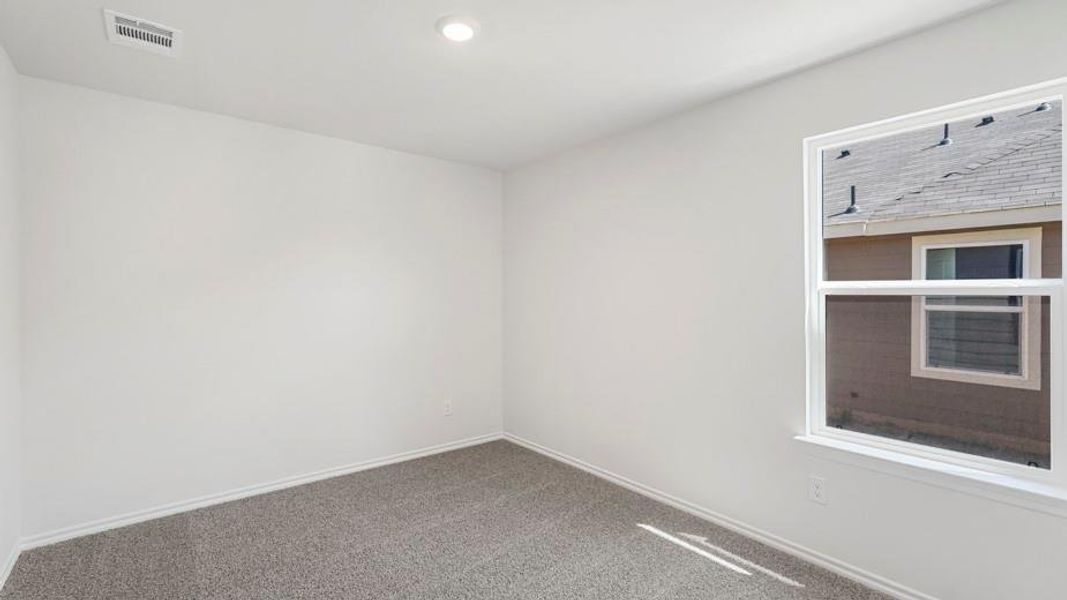 Bright room featuring neutral wall paint, grey carpet flooring, a single window, recessed ceiling lighting, and a ceiling-mounted air vent Bright room featuring neutral wall paint, grey carpet flooring, a single window, recessed ceiling lighting, and a ceiling-mounted air vent