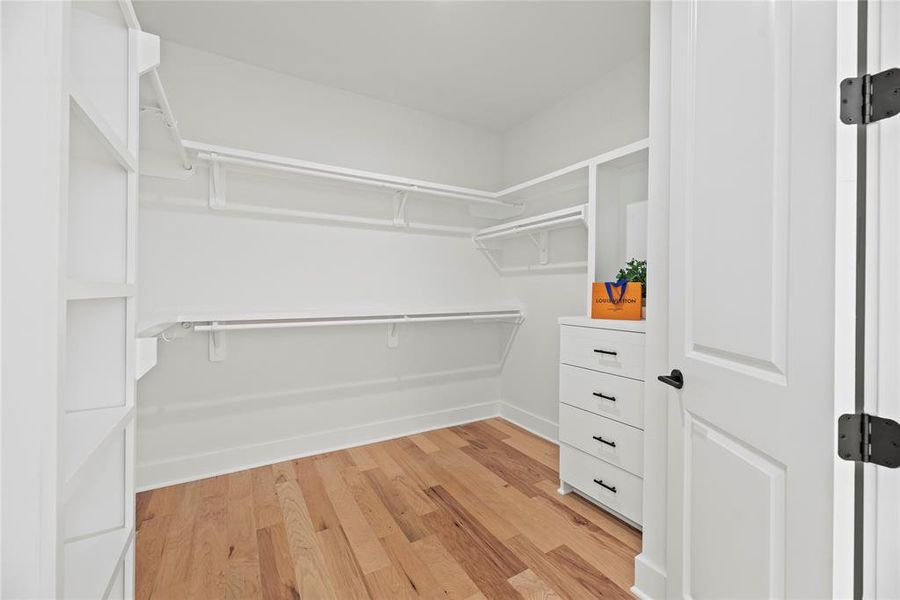 The large primary closet has double doors, built in shelves and drawers.