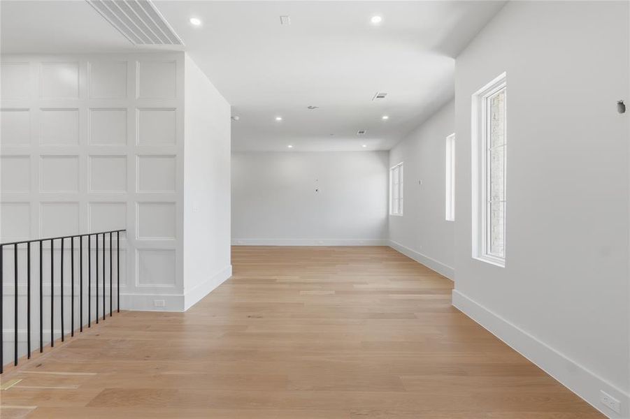 Expansive upstairs game room with board-and-batten detail wall and wide-plank hardwood floors Expansive upstairs game room with board-and-batten detail wall and wide-plank hardwood floors