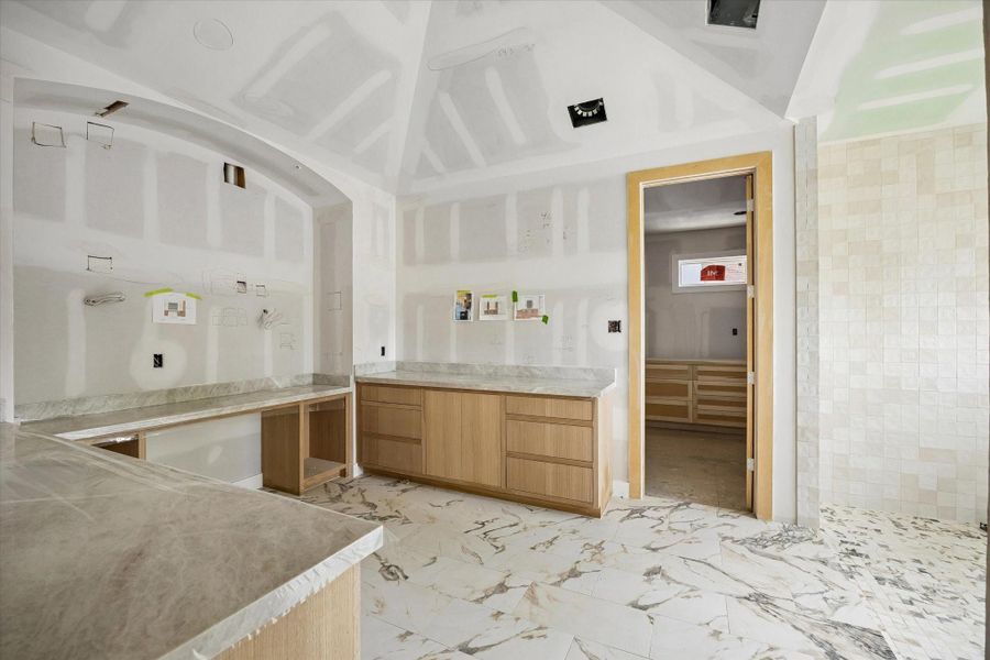 Spa inspired primary bath coming to life with dual vanity layout and a framed walk in shower. Arched detailing and generous ceiling height elevate the space, creating a true retreat within this Oak Forest custom home. Spa inspired primary bath coming to life with dual vanity layout and a framed walk in shower. Arched detailing and generous ceiling height elevate the space, creating a true retreat within this Oak Forest custom home.