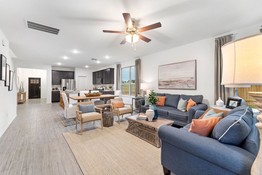 A living room with a large ceiling fan and a wood floor. A living room with a large ceiling fan and a wood floor.
