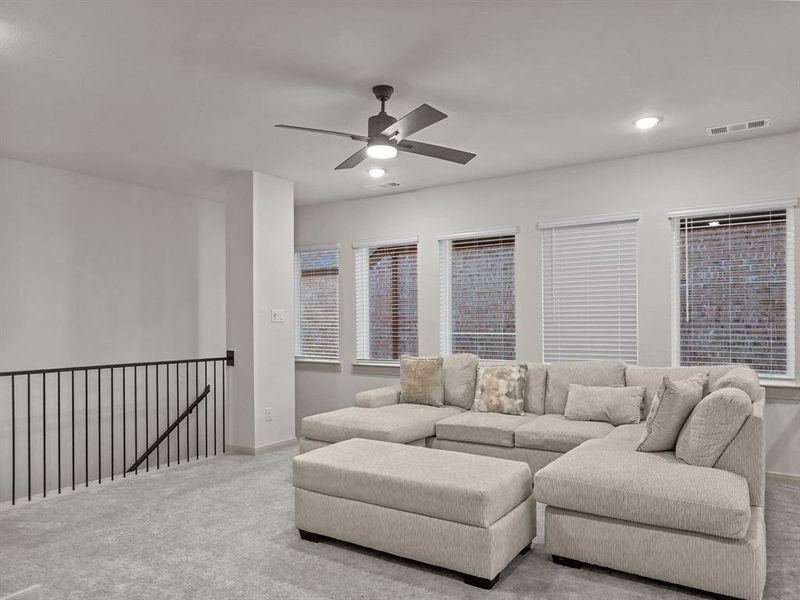 Carpeted living room featuring ceiling fan