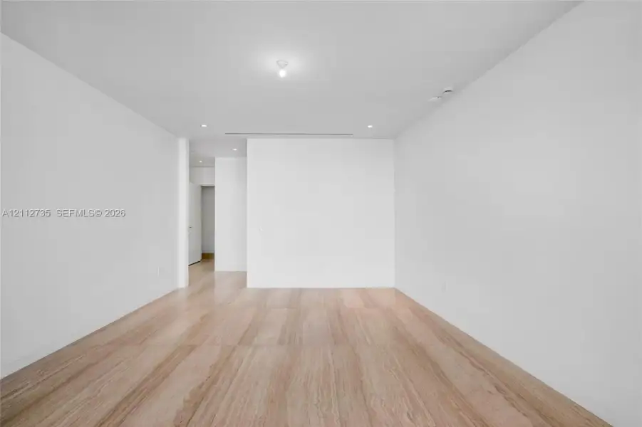 Interior space featuring light wood-finish flooring, smooth white walls, recessed ceiling lighting, and a linear slot ceiling diffuser