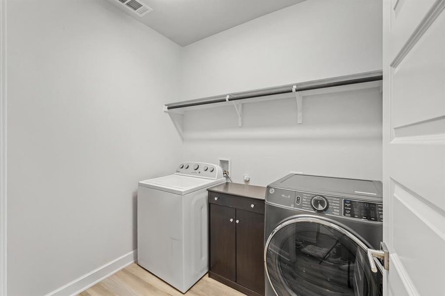 Washroom with light wood-style floors and washer and dryer Washroom with light wood-style floors and washer and dryer