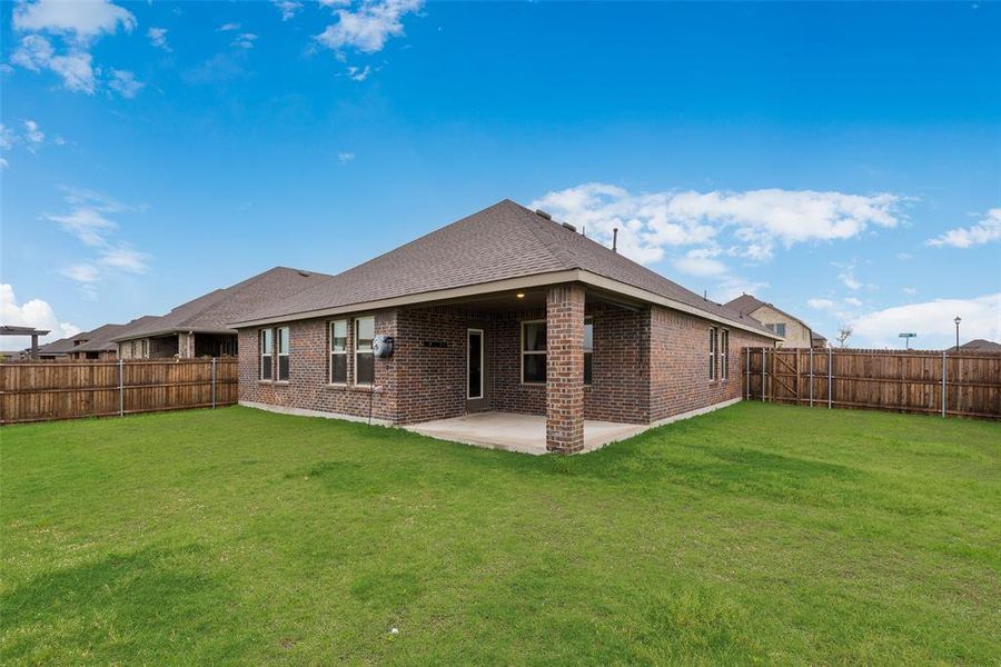 Back of house featuring a patio, brick siding, a fenced backyard, and a yard