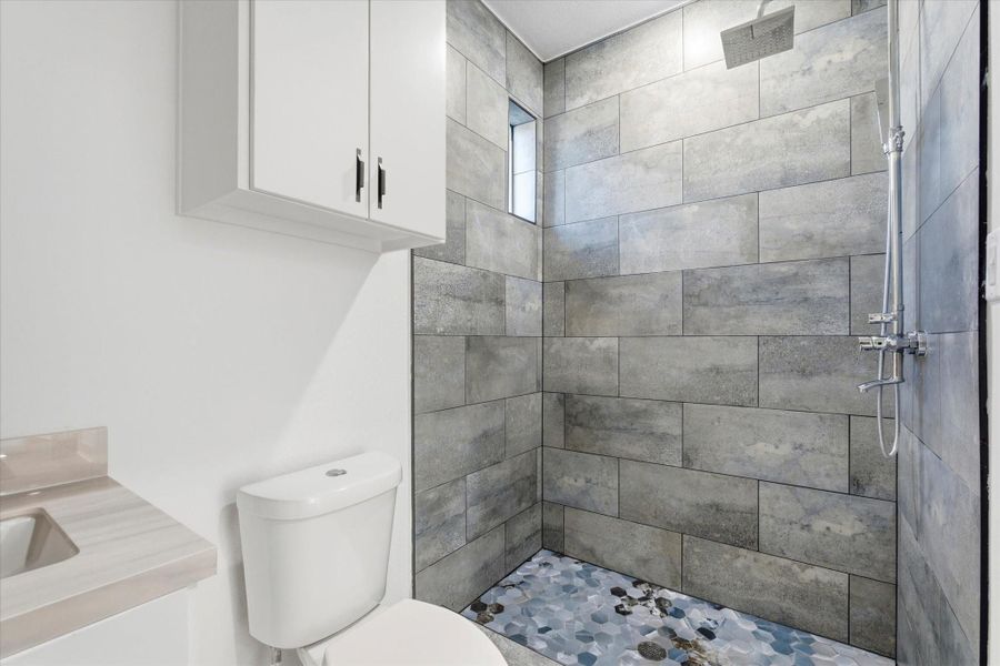 Moody gray and blue tones define this hall bathroom, featuring a modern exposed shower system and soft natural light from a peekaboo window. Moody gray and blue tones define this hall bathroom, featuring a modern exposed shower system and soft natural light from a peekaboo window.