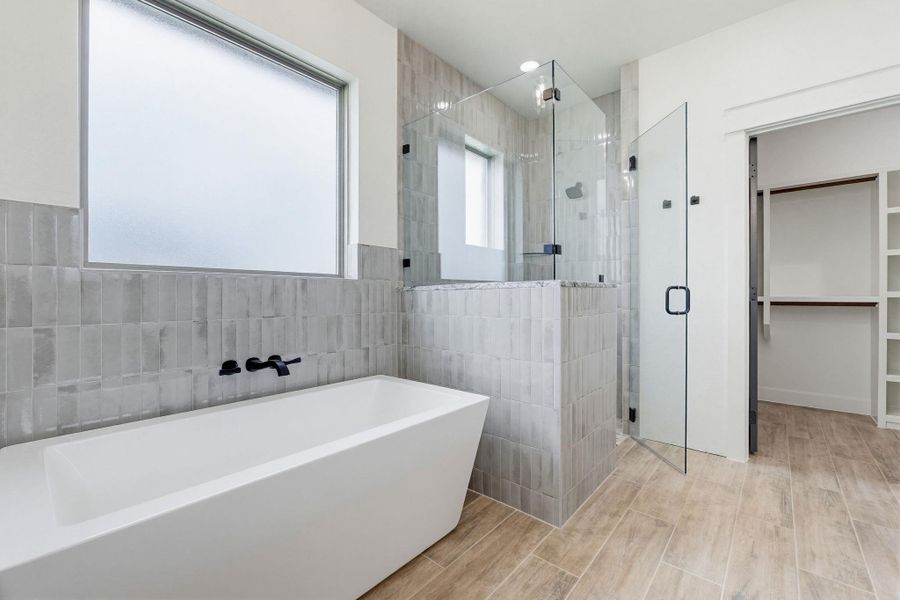 Indulge in a tranquil retreat featuring a spacious soaking tub and a sleek, glass-enclosed shower. Indulge in a tranquil retreat featuring a spacious soaking tub and a sleek, glass-enclosed shower.